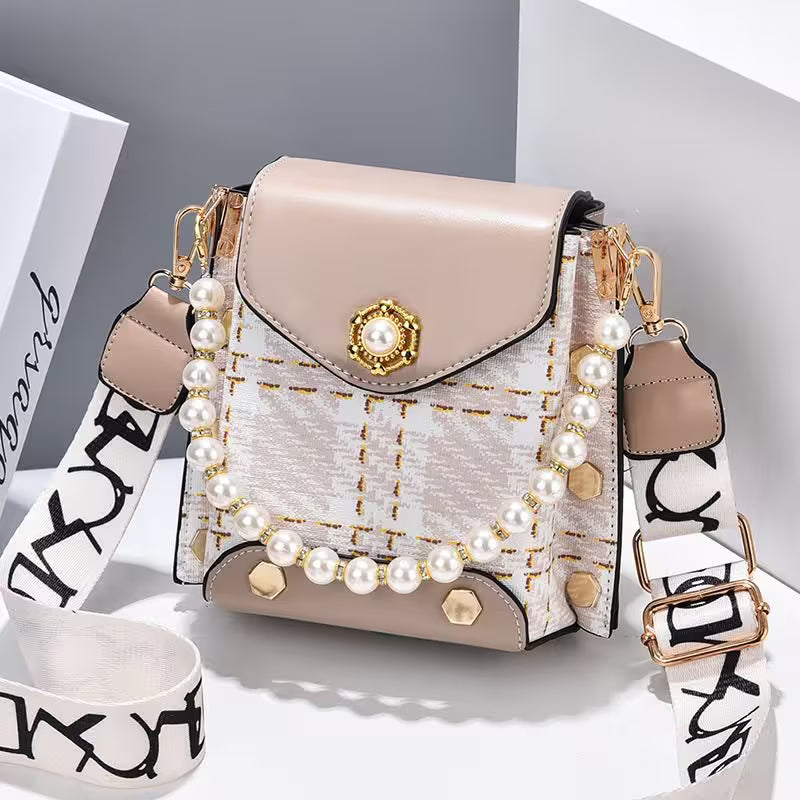 Beige handbag with pearl embellishments on a white surface