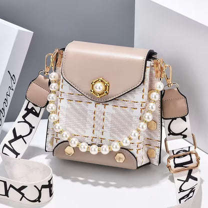 Beige handbag with pearl embellishments on a white surface