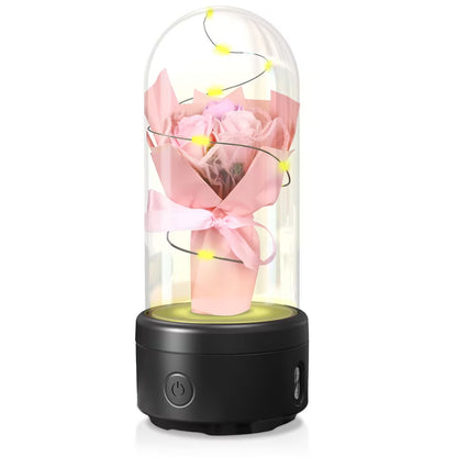 Decorative lamp with pink roses and fairy lights inside a glass dome on a white background