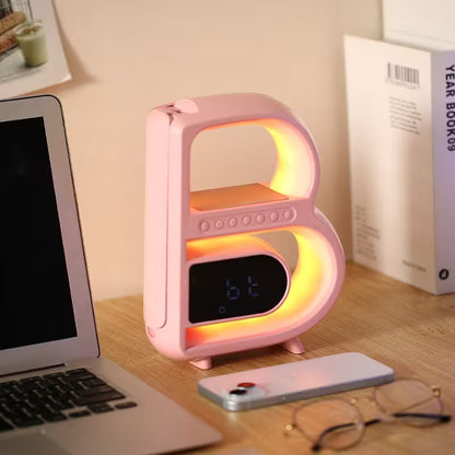 Pink letter 'B' lamp on a desk with a laptop and phone