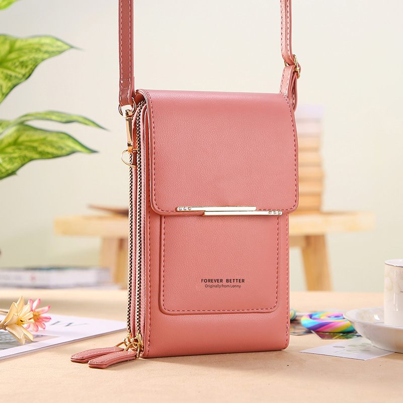Pink crossbody bag on a desk with a blurred background