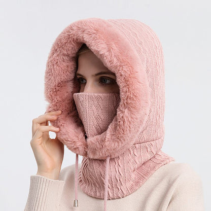 Person wearing a pink knitted hood and face mask on a light gray background