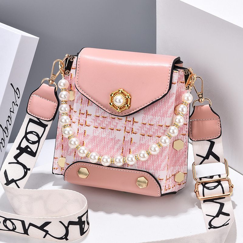 Pink handbag with pearl details and a strap on a white background