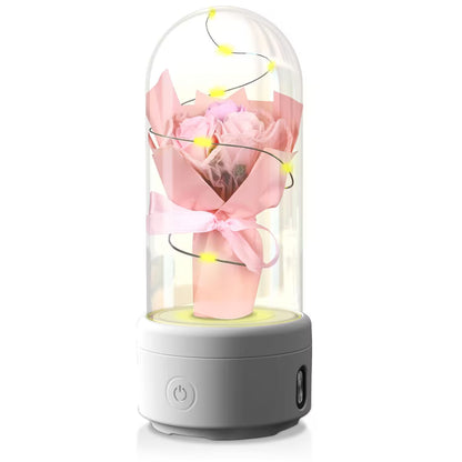 Decorative lamp with pink roses and LED lights inside a glass dome on a white background