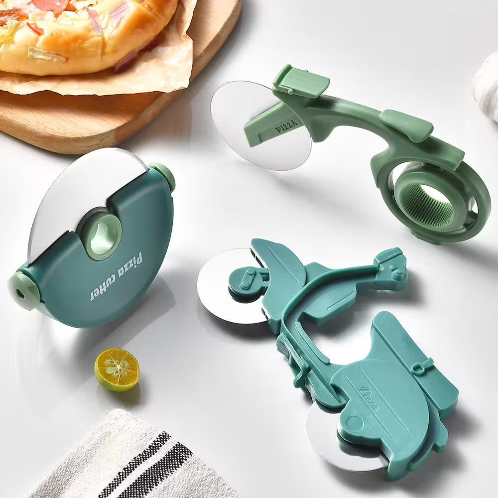 Two pizza cutters on a white surface with a pizza and lemon slice in the background.