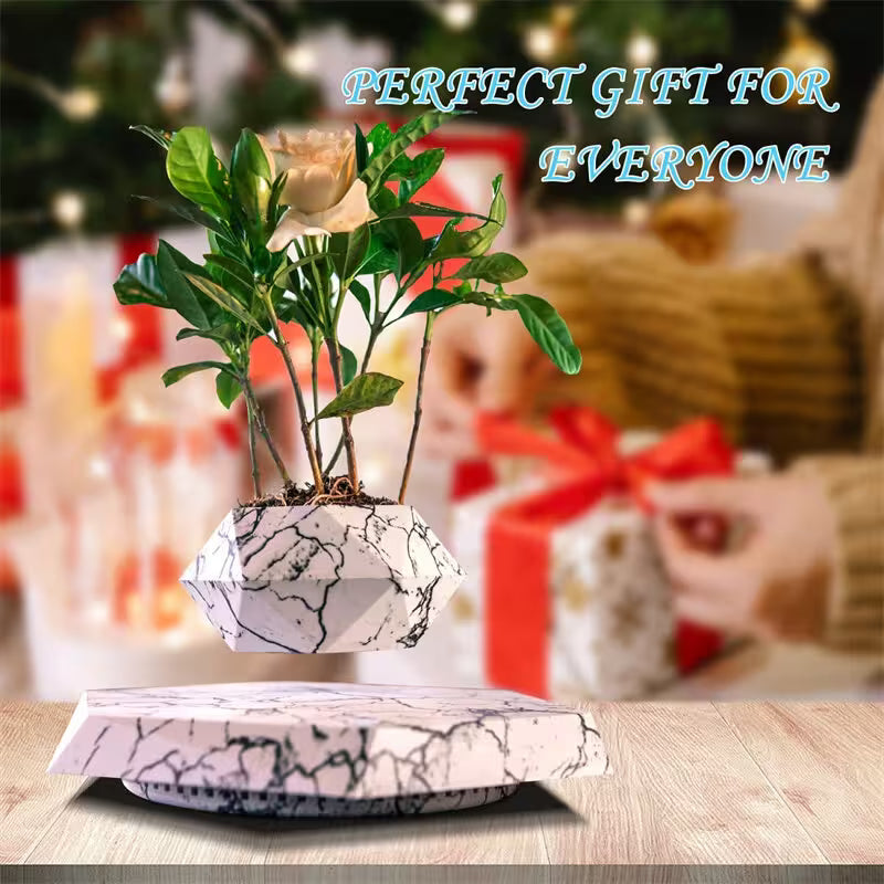 Decorative plant pot with marble design on a wooden surface, with blurred gift-wrapped presents and Christmas tree in the background.