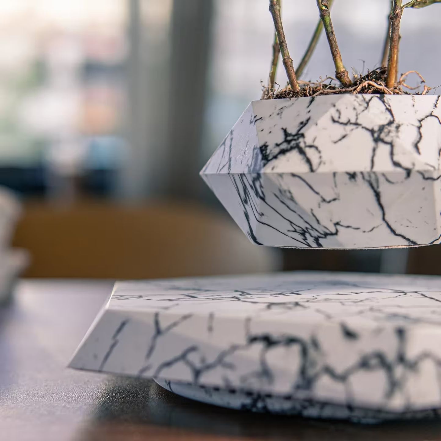 Marble-patterned geometric planters on a blurred background