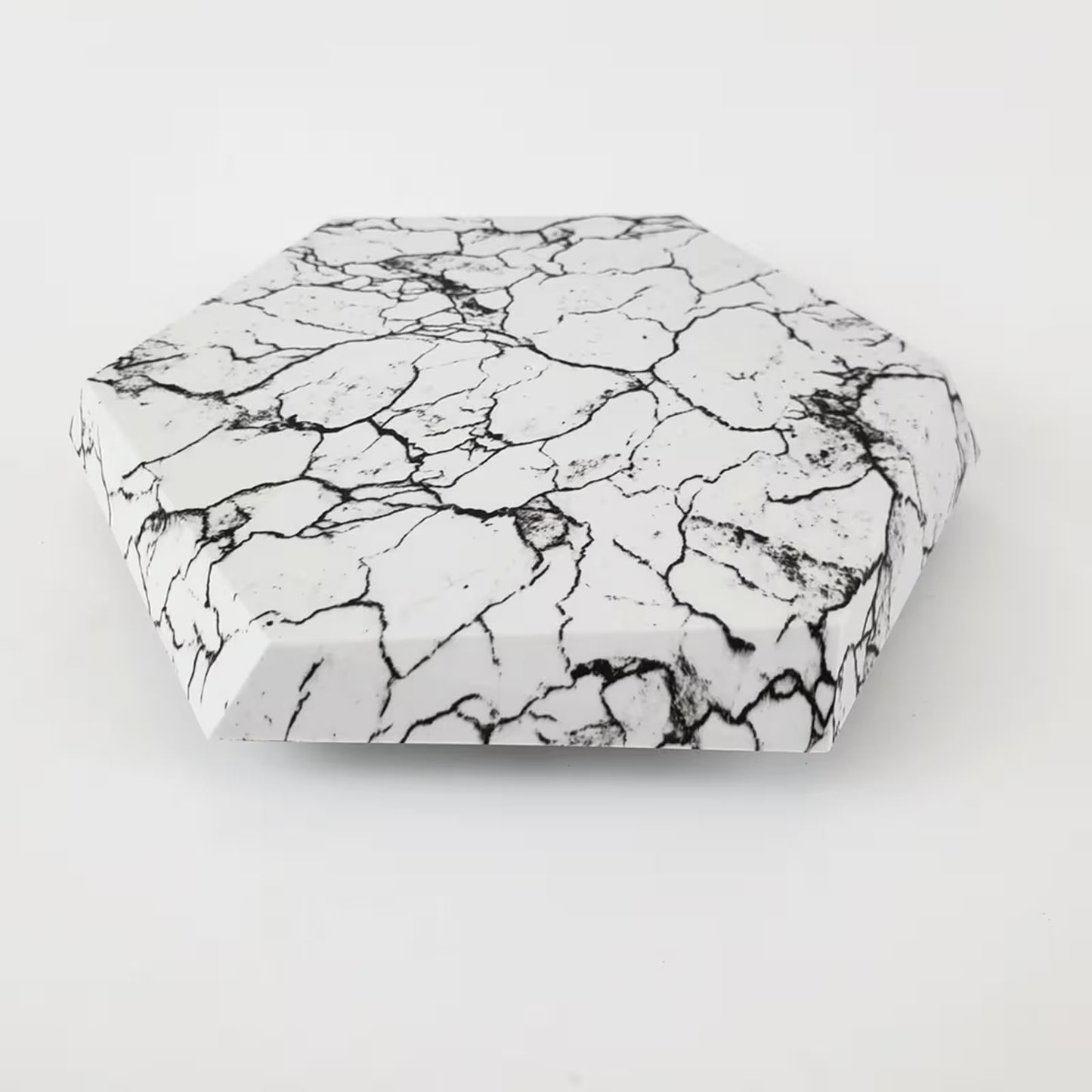 Hexagonal stone with black and white marbled pattern on a light gray background