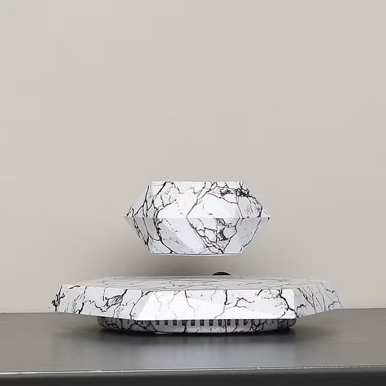 Marble-patterned geometric lamp on a reflective surface with a neutral background