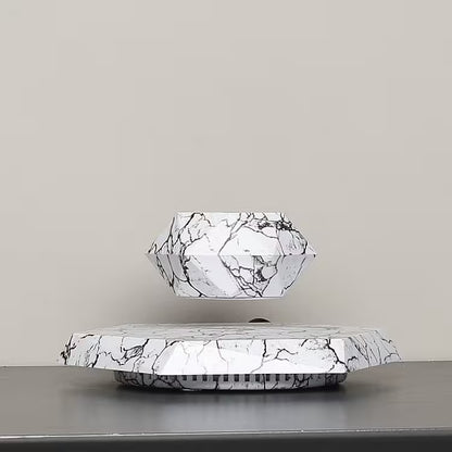 Marble-patterned geometric lamp on a reflective surface with a neutral background