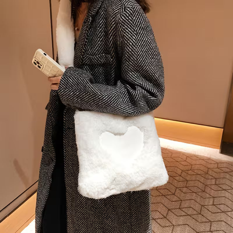 Person wearing a gray coat holding a white fluffy bag and a phone.