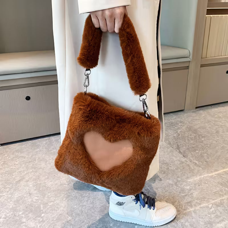Person holding a brown fluffy handbag with a heart design.