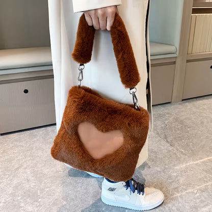 Person holding a brown fluffy handbag with a heart design.