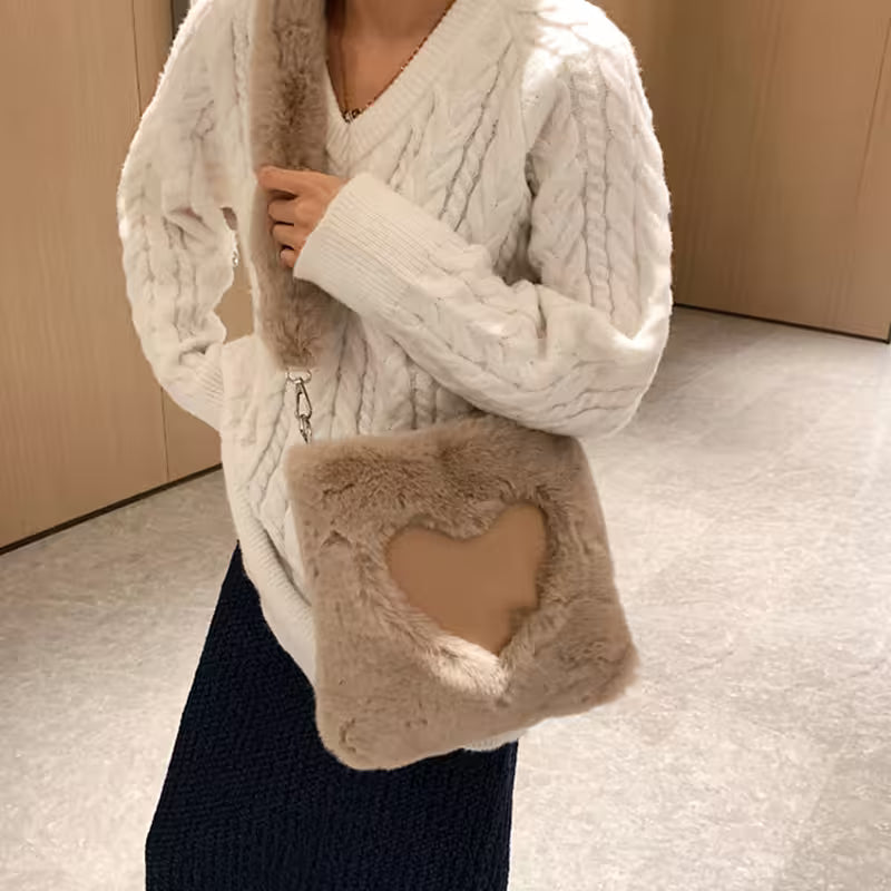 Person wearing a white cable knit sweater with a fur-lined hood and matching pouch.