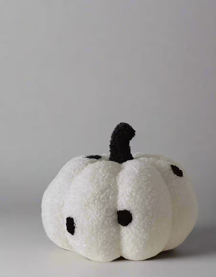 White plush pumpkin with black details on a gray background
