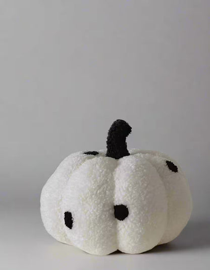 White plush pumpkin with black details on a gray background