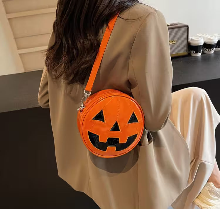 Person wearing a beige coat with an orange pumpkin-shaped bag.