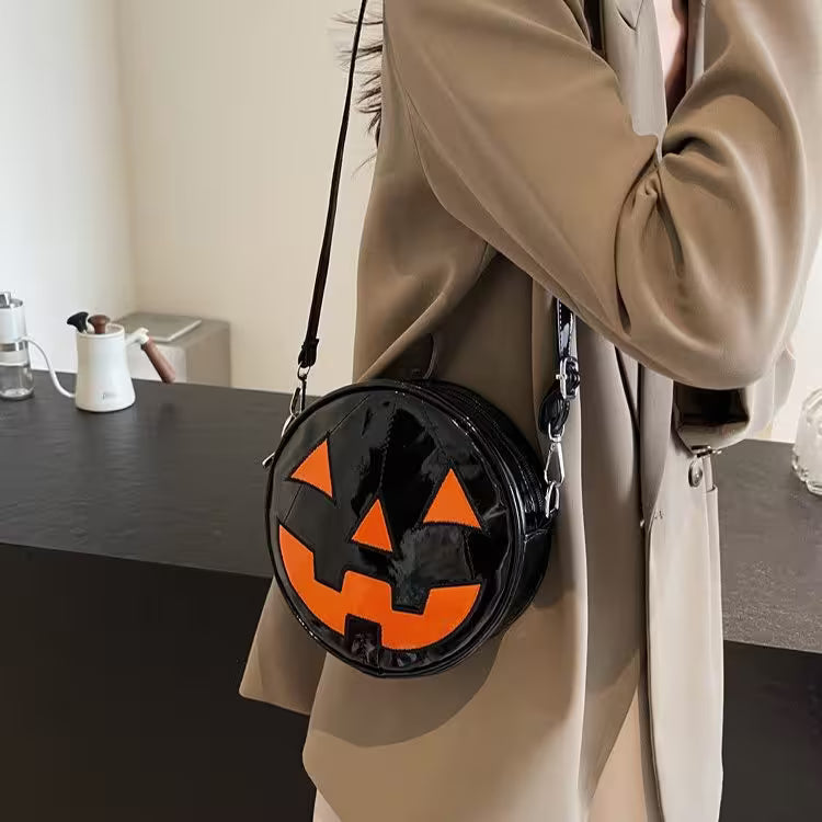 Person wearing a beige coat holding a black Halloween-themed bag with orange face design.