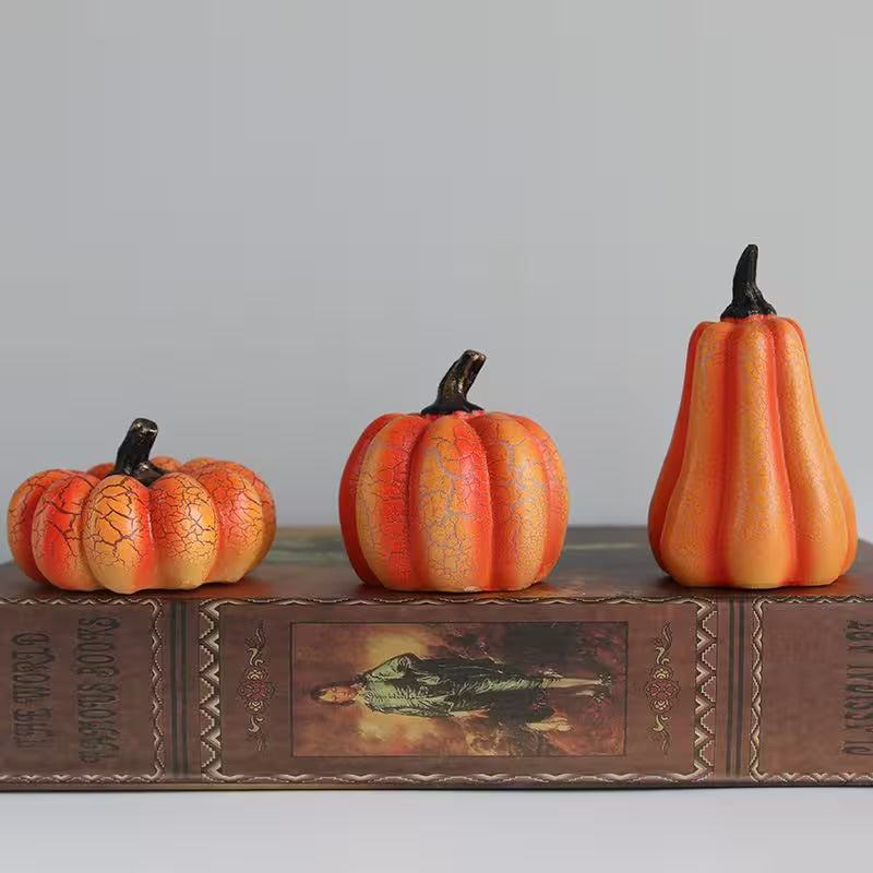 Three decorative pumpkins on a vintage book with a gray background