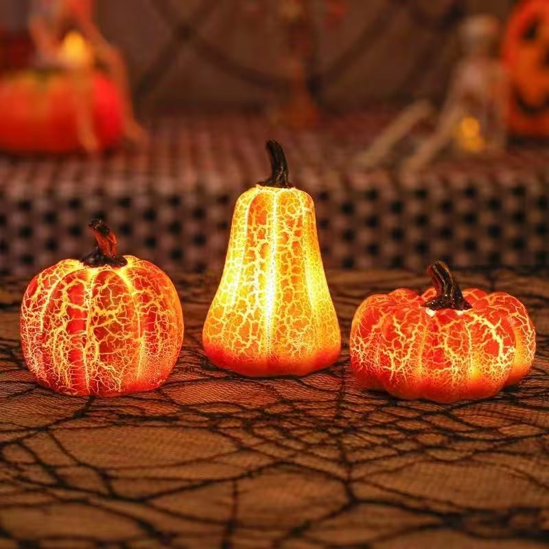 Three glowing LED pumpkins on a textured surface with blurred Halloween-themed background