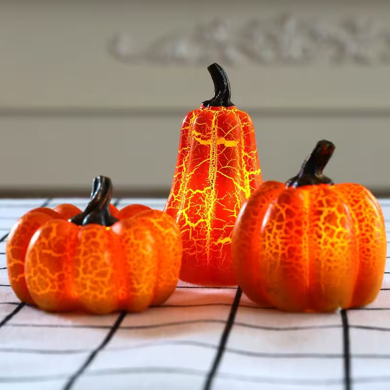Three decorative pumpkins with a cracked texture on a white surface.