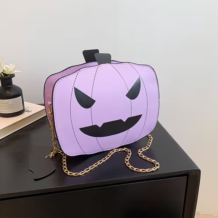 Purple pumpkin-shaped bag with a gold chain on a black surface