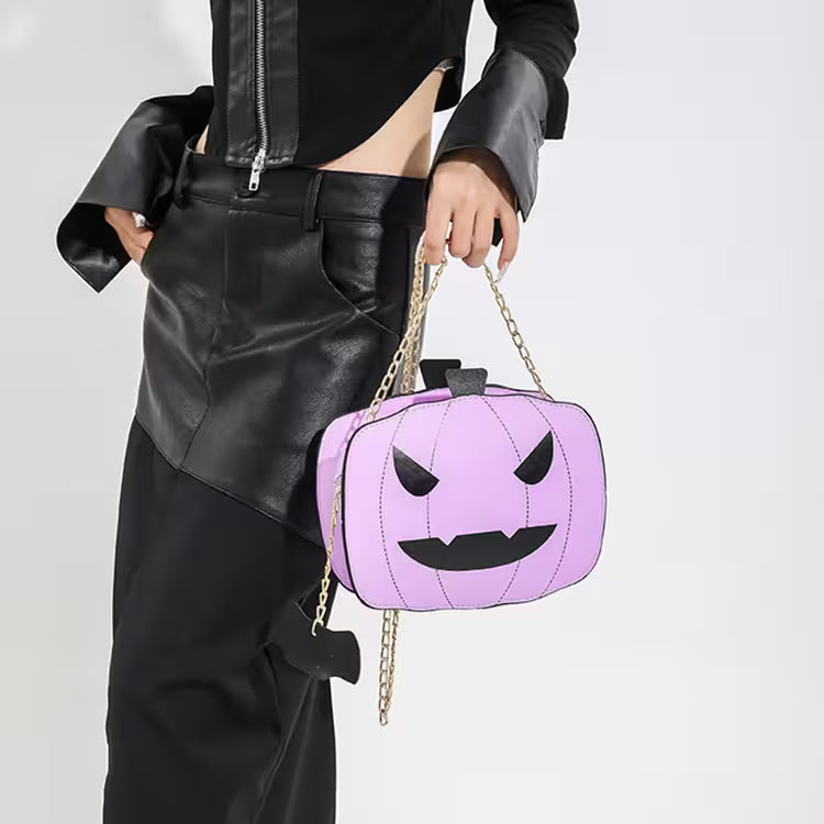 Person holding a purple pumpkin-shaped handbag with a chain strap on a white background
