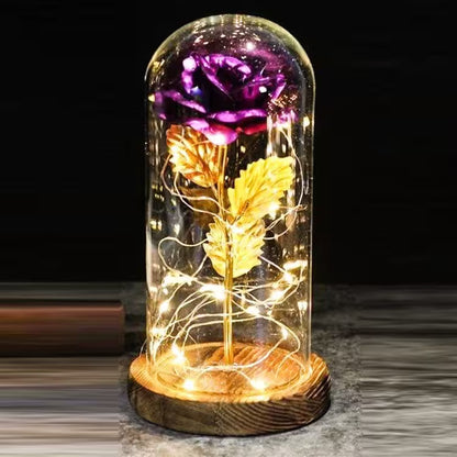 Decorative glass dome with glowing flowers on a wooden base against a dark background