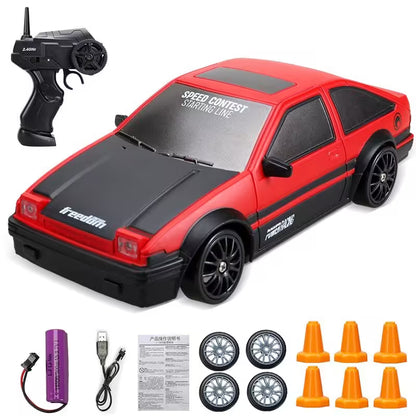 Red and black toy car with remote control, batteries, and accessories on a white background