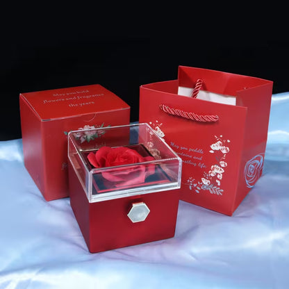 Red gift box with a rose inside, accompanied by a matching red packaging bag on a white surface.