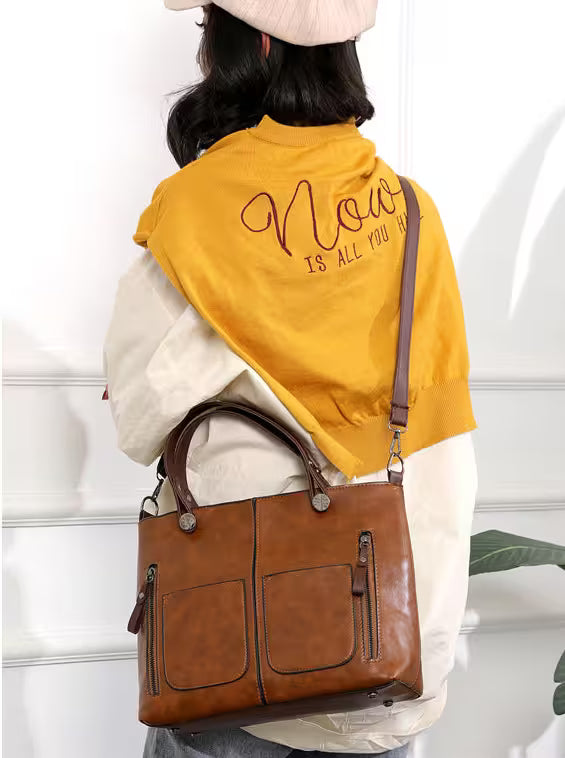 Person wearing a yellow scarf with text, holding a brown leather bag against a white background