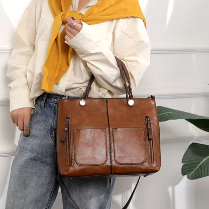 Person holding a brown leather handbag with a neutral background