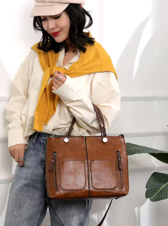 Woman holding a brown leather handbag against a white background