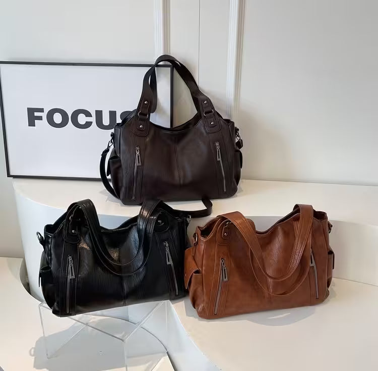Three handbags in black, brown, and another color on a white surface with a 'FOCUS' sign in the background.