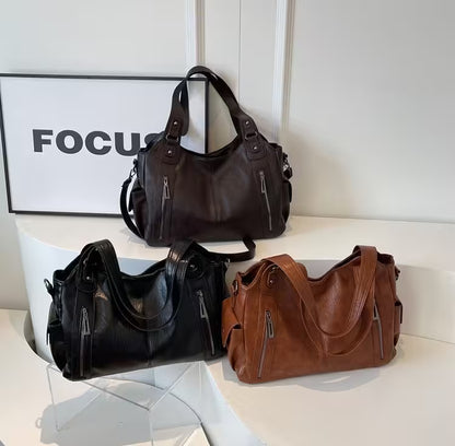 Three handbags in black, brown, and another color on a white surface with a 'FOCUS' sign in the background.