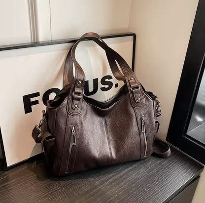 Brown leather handbag on a surface with a 'FOCUS' sign in the background