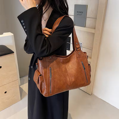 Person holding a brown leather handbag in an indoor setting
