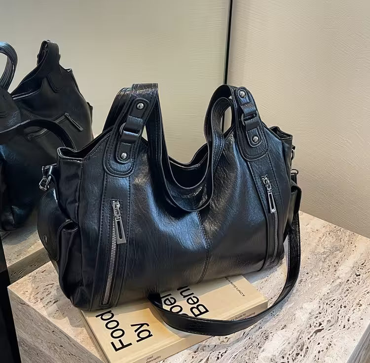 Black leather handbag on a stone surface with a blurred background