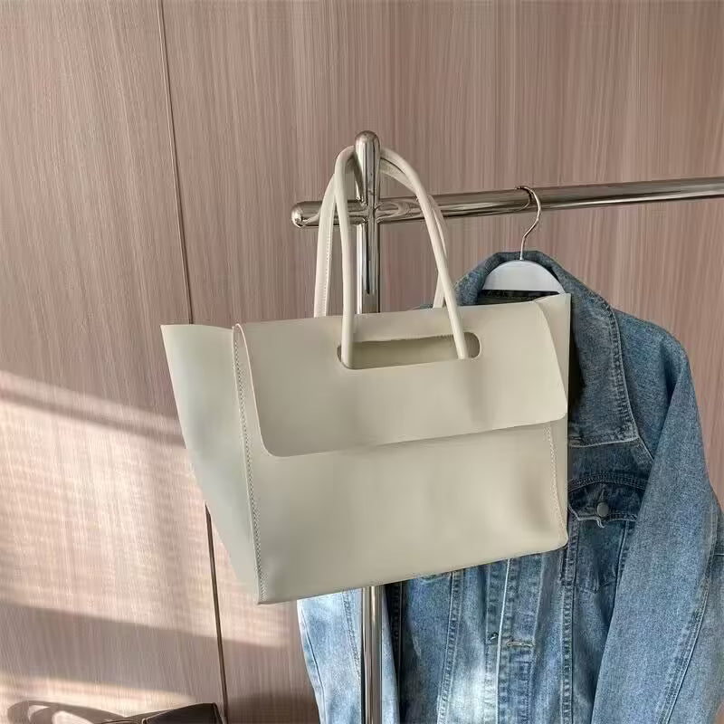 Beige handbag hanging on a rack with a denim jacket