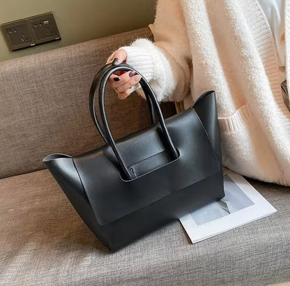 Person holding a black handbag on a couch