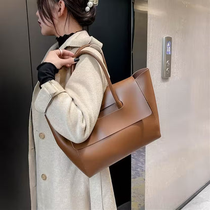 Woman holding a brown leather handbag in an elevator.