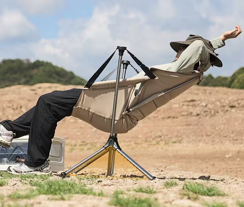 Person relaxing in a portable chair with a stand outdoors