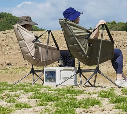 Two people sitting in portable folding chairs outdoors with a cooler between them.