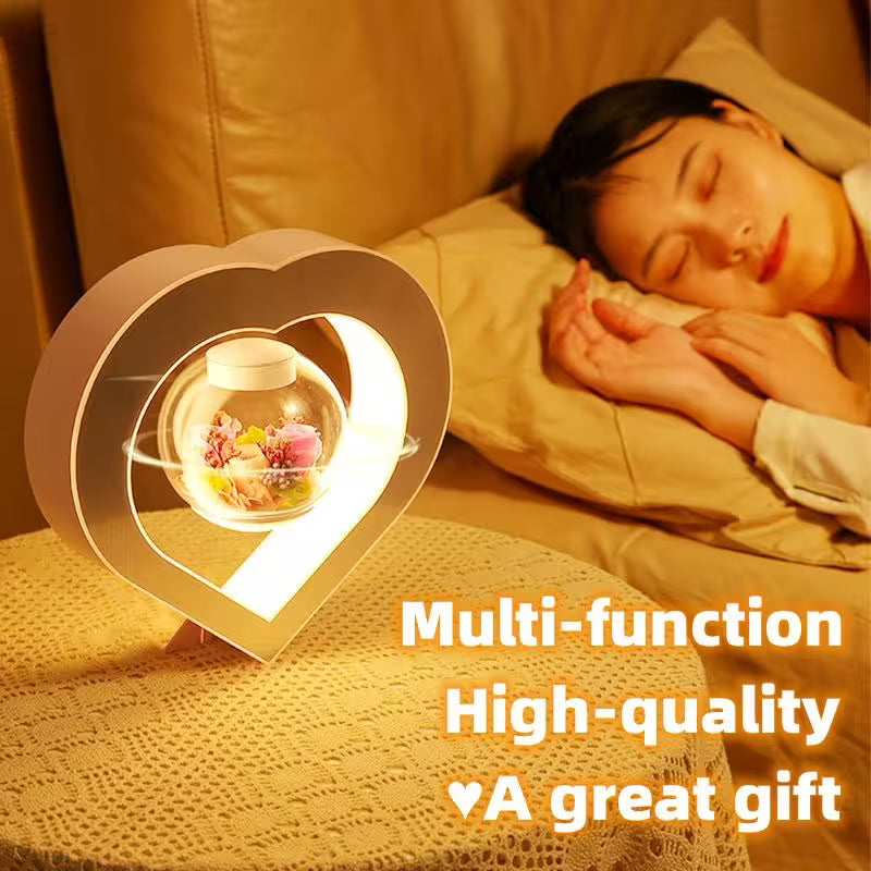 Heart-shaped night light on a surface with a person sleeping in the background
