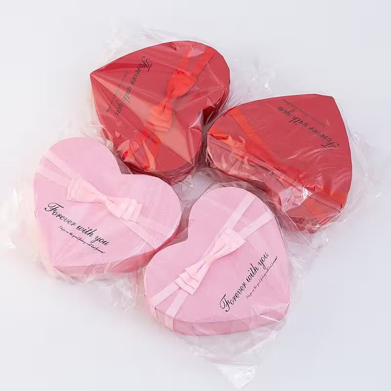 Heart-shaped pink and red gift boxes with ribbons on a white background