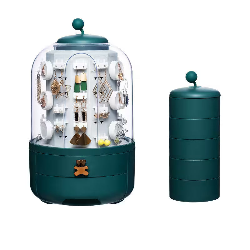 Green jewelry display case with transparent lid containing earrings and necklaces on a white background