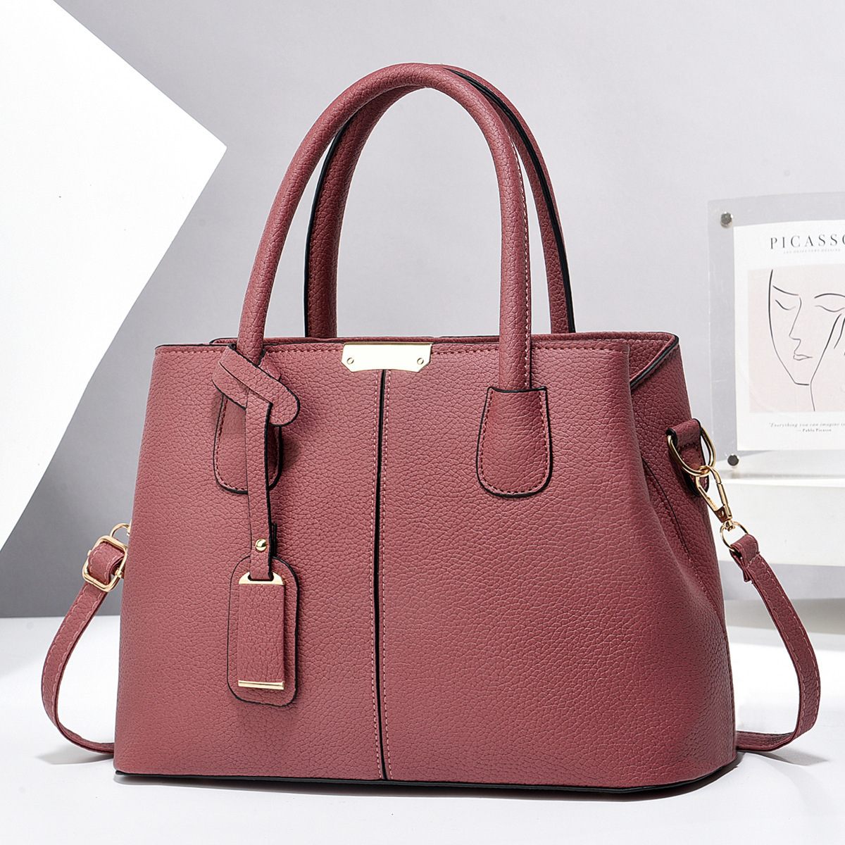 Pink handbag with gold accents on a white background