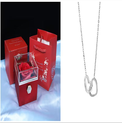 Red gift bag with a rose and a silver necklace on a white background
