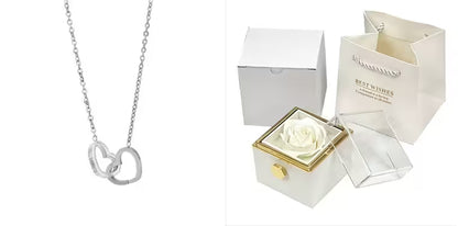 Silver necklace with a heart pendant next to a white box containing a preserved rose.