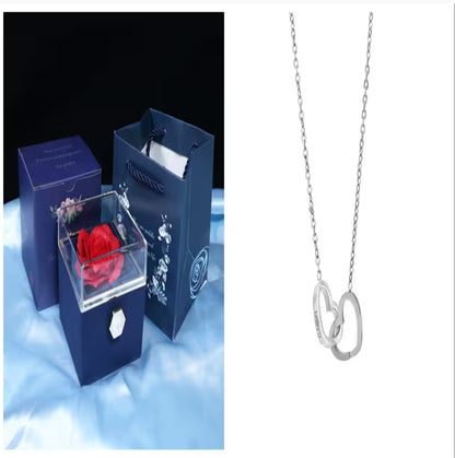 Blue jewelry box with a red rose and a silver necklace with heart pendants on a white background.